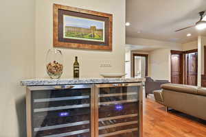 Indoor dry bar featuring beverage cooler, light wood-style floors, ceiling fan, and recessed lighting