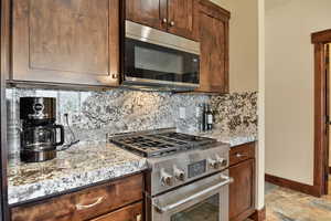 Kitchen with appliances with stainless steel finishes, backsplash, and baseboards