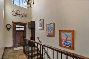 Foyer entrance featuring a chandelier, a towering ceiling, dark stone finish flooring, and baseboards