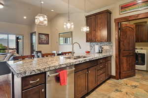 Kitchen featuring washer / clothes dryer, dishwasher, a sink, a peninsula, and decorative light fixtures