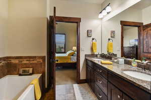 Ensuite bathroom featuring a garden tub, double vanity, and tile patterned floors
