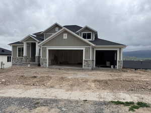 Craftsman inspired home with stone siding, a garage, and board and batten siding