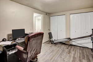 Home office with wood finished floors and a textured ceiling