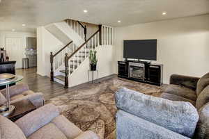 Living area with stairway, wood finished floors, recessed lighting, and baseboards