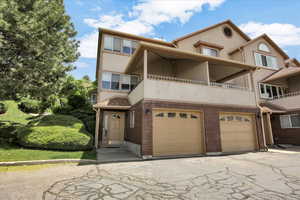 Townhome / multi-family property with an attached garage, stucco siding, driveway, and brick siding