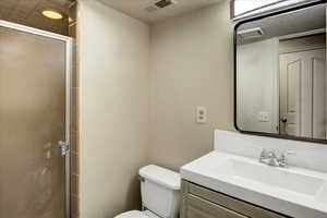 Bathroom featuring a shower stall, toilet, and vanity