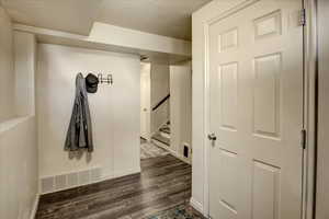 Hallway with dark wood finished floors, baseboards, a textured ceiling, and stairway