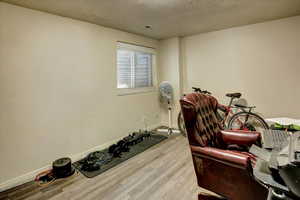 Workout room with wood finished floors, a textured ceiling, and baseboards