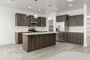 Kitchen featuring appliances with stainless steel finishes, light countertops, decorative backsplash, light wood-style flooring, and recessed lighting