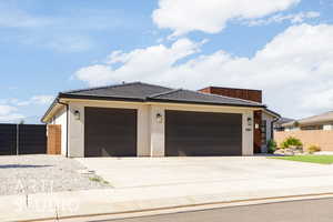 View of front facade featuring driveway, an attached garage, a tiled roof, and stucco siding