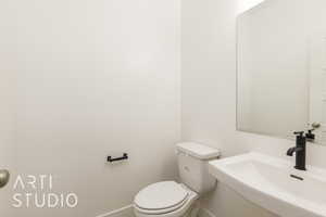Half bathroom featuring a sink, toilet, and baseboards