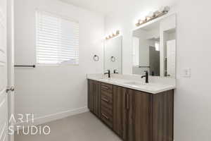 Full bath with double vanity, tile patterned floors, and baseboards