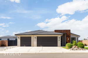 Contemporary home featuring driveway, stucco siding, a tile roof, and a garage