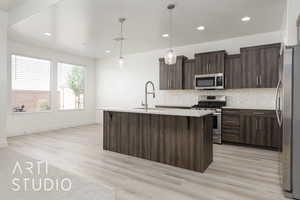 Kitchen with appliances with stainless steel finishes, a sink, baseboards, light countertops, and backsplash