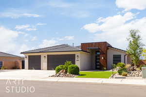 Contemporary home featuring stucco siding, driveway, a garage, and a tiled roof