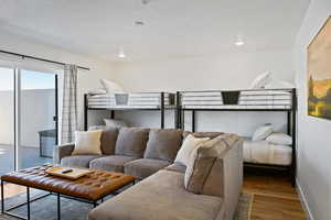 Bedroom featuring wood finished floors, access to exterior, baseboards, and a textured ceiling