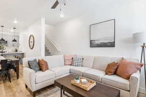 Living room with light wood finished floors, ceiling fan, stairs, and recessed lighting