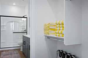 Full bath featuring a stall shower, toilet, vanity, wood finished floors, and radiator heating unit