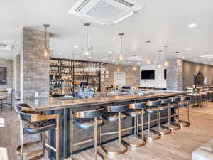Indoor wet bar featuring wood finished floors and decorative columns