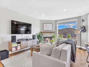 Living room with wood finished floors, a stone fireplace, recessed lighting, and baseboards