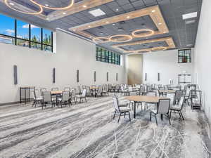 Carpeted dining room featuring a towering ceiling, a raised ceiling, recessed lighting, and baseboards