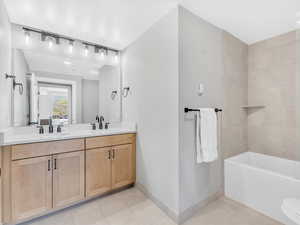 Full bathroom featuring tile patterned floors, baseboards, double vanity, and ensuite bath