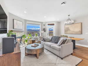 Living room with baseboards, wood finished floors, a fireplace, recessed lighting, and a chandelier