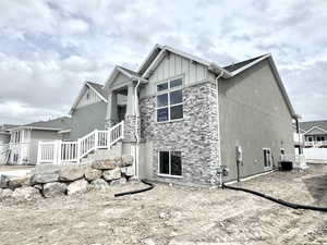 View of home's exterior with stone siding, board and batten siding, and central AC unit