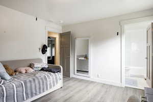 Bedroom featuring light wood-style floors and ensuite bath