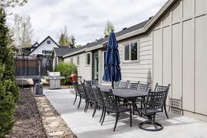View of patio with a trampoline, outdoor dining area, and area for grilling