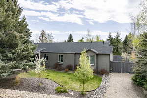 Single story home with a gate, roof with shingles, and a front lawn