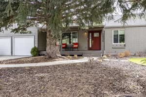 Single story home featuring covered porch, brick siding, a shingled roof, an attached garage, and driveway