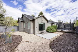 Back of property featuring a trampoline, board and batten siding, a fenced backyard, and a patio