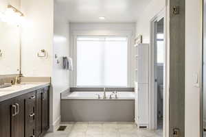 Bathroom featuring double vanity, a garden tub, tile patterned floors, and toilet