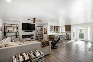 Living area with a fireplace, wood finished floors, a ceiling fan, recessed lighting, and baseboards