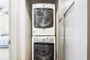 Laundry area featuring stacked washer and clothes dryer and a ceiling fan