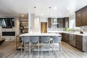 Kitchen featuring stainless steel dishwasher, a sink, dark brown cabinetry, a kitchen bar, and recessed lighting