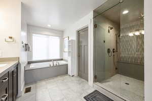 Full bath with a stall shower, a bath, vanity, and recessed lighting