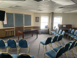 Interior room with a paneled ceiling, a wainscoted wall, and carpet flooring.