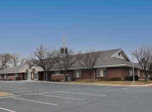 View of building exterior featuring uncovered parking and cooling unit