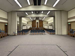 View of carpeted recreational space and chapel with floor-to-ceiling room dividers retracted.