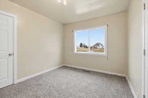 Carpeted spare room featuring baseboards