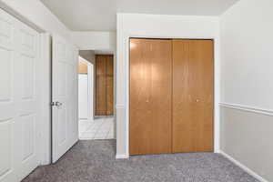 Unfurnished bedroom featuring carpet floors, a closet, and tile patterned flooring