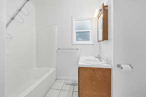 Full bath with vanity, light tile patterned flooring, and shower / washtub combination