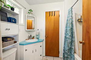 Back Unit's Full bath with tile patterned flooring, toilet, vanity, and shower / bathtub combination with curtain