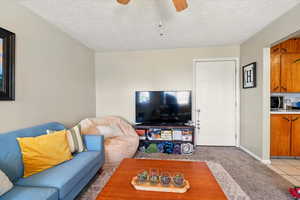 Back Unit's Living room featuring ceiling fan, light carpet, a textured ceiling, and light tile patterned floors