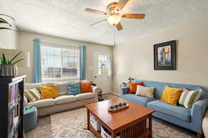 Back Unit's Living room with a ceiling fan, a textured ceiling, and light colored carpet