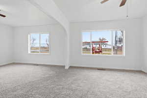 Unfurnished room with a ceiling fan, carpet floors, and healthy amount of natural light