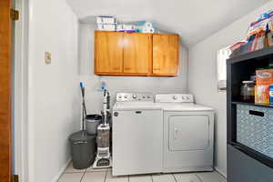 Back Unit's Washroom featuring washing machine and clothes dryer, cabinet space, light tile patterned floors, and baseboards