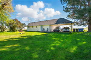 Rear view of property featuring a lawn and a carport